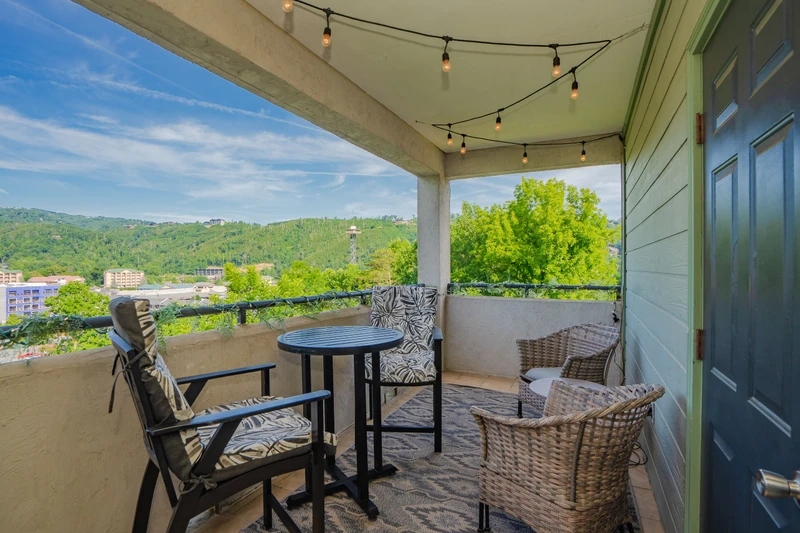 Sip your morning coffee on this covered balcony while soaking in stunning mountain views. Cozy seating and string lights create the perfect spot for relaxation.